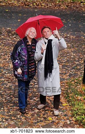 Middleaged couple with an umbrella goes for a walk in rainy weather View Large Photo Image Stock Image - Middleaged couple with an umbrella goes for a walk in rainy weather. Fotosearch