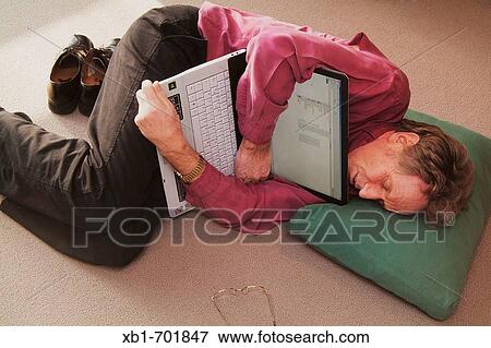 Middleaged man is lying on the floor with a notebook View Large Photo Image Stock Photo - Middleaged man is lying on the floor with a notebook. Fotosearch