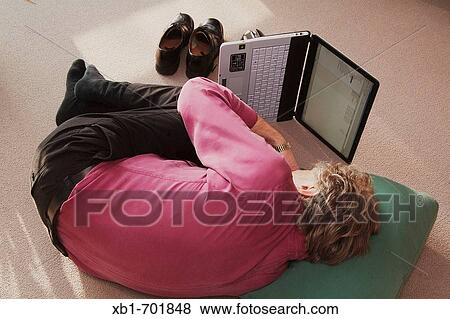 Middleaged man is lying on the floor with a notebook View Large Photo Image Stock Photo - Middleaged man is lying on the floor with a notebook. Fotosearch