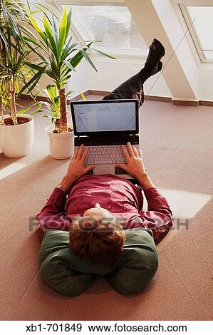 Middleaged man is lying on the floor with a notebook View Large Photo Image Stock Photo - Middleaged man is lying on the floor with a notebook. Fotosearch