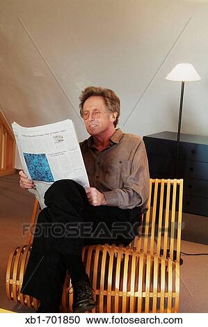Middleaged man is reading a newspaper on a chair View Large Photo Image Stock Image - Middleaged man is reading a newspaper on a chair. Fotosearch