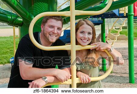 Midwest couple aged 22 playing and dating in park at monkey bars and hugging playing View Large Photo Image Picture - Midwest couple aged 22 playing and dating in park at monkey bars and hugging playing. Fotosearch