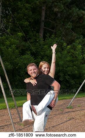 Stock Photo - Midwest couple aged 22 playing and dating in park at swing and hugging playing. Fotosearch