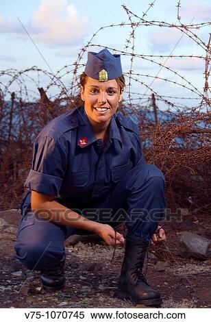 Military girl tying her boots with a spike fence in background View Large Photo Image Stock Photography - Military girl tying her boots with a spike fence in background. Fotosearch