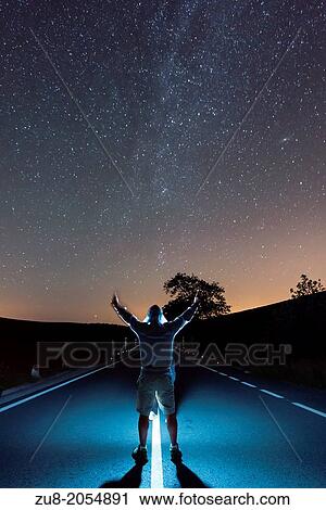 Stock Image - Milky Way aligned with the road, with someone Backs against sending halt a flash.. Fotosearch