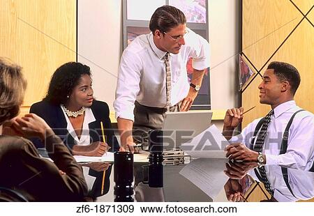 Stock Photo - Mixed race and ethnic office business situation with team working together in modern office indoors with men and women. Fotosearch