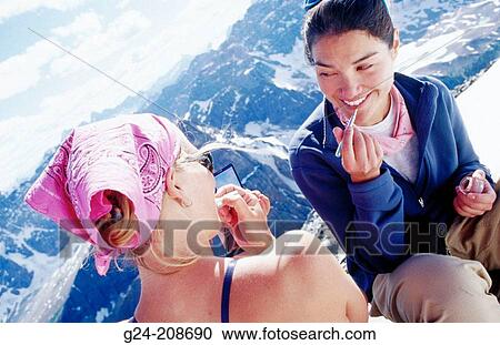 Stock Image - Mixed race ladies applying makeup at mountain summit. Banff NP. Canada. Fotosearch