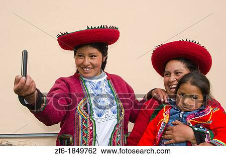 Stock Image - Modern life in Peru family in traditional dress and hat taking photo with cell phone communicating. Fotosearch