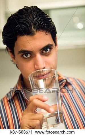 Modern young Indian man in kitchen drinking water. View Large Photo Image Stock Image - Modern young Indian man in kitchen drinking water.. Fotosearch