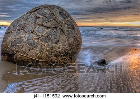 Stock Image - Moeraki boulders at dawn as SW front passes overhead, near Oamaru, Otago,. Fotosearch