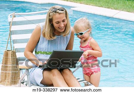 Stock Photo - mom and daughter poolside with laptop. Fotosearch