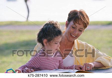 mom and daughter reading together in park View Large Photo Image Stock Image - mom and daughter reading together in park. Fotosearch