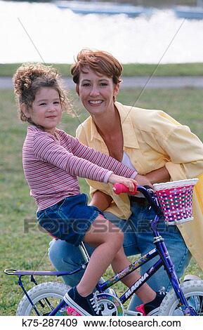 Stock Photo - mom and her young daughter on her bike. Fotosearch