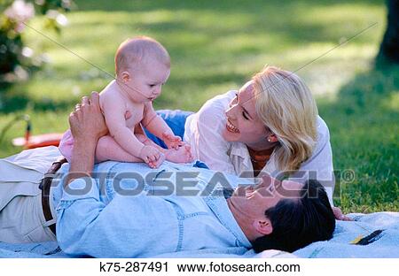 Mom, dad, and baby on blanket outdoors View Large Photo Image Stock Image - Mom, dad, and baby on blanket outdoors. Fotosearch