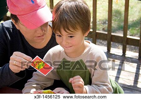 Mom helping son playing card game Apples to Apples outside on deck Clitherall Minnesota MN USA View Large Photo Image Stock Photography - Mom helping son playing card game Apples to Apples outside on deck Clitherall Minnesota MN USA. Fotosearch