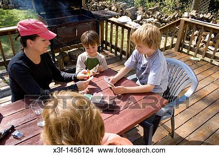 Picture - Mom kids and Grandma playing the card game Apples to Apples on the deck Clitherall Minnesota MN USA. Fotosearch