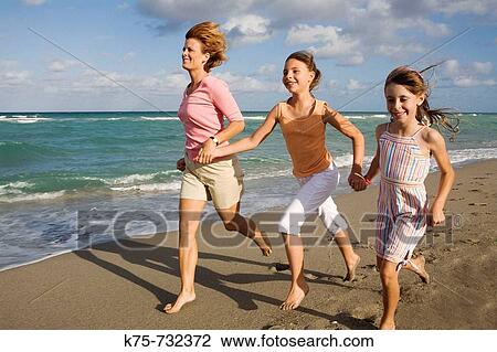 Stock Image - mom running with her daughter and friend at bach. Fotosearch