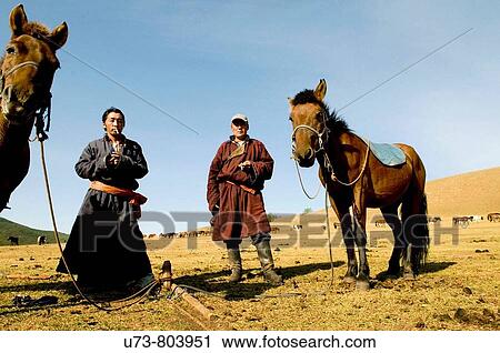Stock Image - Mongolian nomads enjoy a cigarette break in the vast Mongolian grasslands. Fotosearch