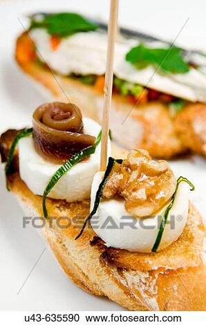 Stock Image - ? Montaditos?. Spanish canap?: cheese with nuts and marinated anchovies.. Fotosearch