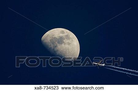 Stock Image - Moon rising in the fourth and condensation trail of airplane. Fotosearch