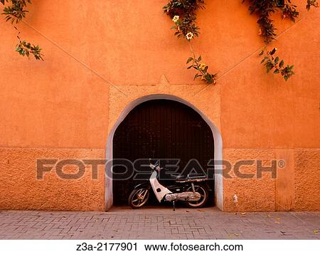 Stock Image - Moped parked in front of a door in Marrakech, Morocco.. Fotosearch