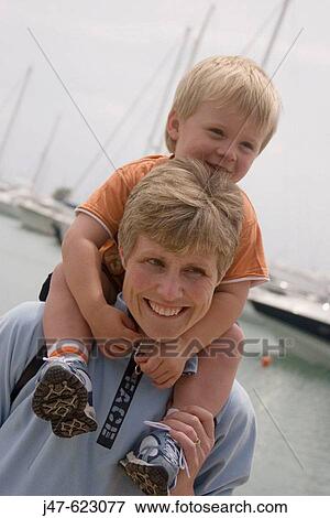Mother 40, and son, 2, boy sitting on Mums shoulders, both smiling View Large Photo Image Stock Photo - Mother 40, and son, 2, boy sitting on Mums shoulders, both smiling. Fotosearch