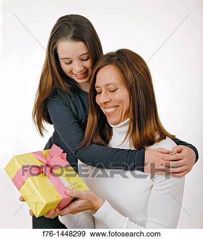Mother 40s holding wrapped gift given to her by her daughter who is hugging her, MR G060511-23 View Large Photo Image Stock Photo - Mother 40s holding wrapped gift given to her by her daughter who is hugging her, MR G060511-23. Fotosearch