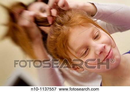 Stock Photo - Mother adjusting the hair of her preteen redhead daughter. Fotosearch