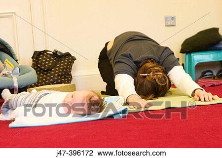 Stock Image - Mother and baby on the floor doing yoga. Fotosearch