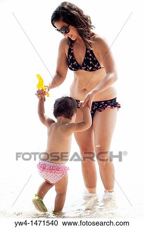 Stock Image - Mother and child playing in the water on the beach. Fotosearch
