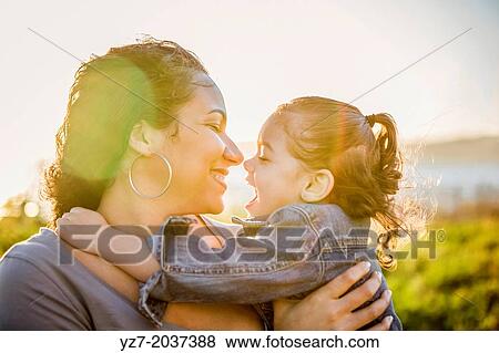 Mother and daughter embracing with the sun behind them. View Large Photo Image Stock Photo - Mother and daughter embracing with the sun behind them.. Fotosearch