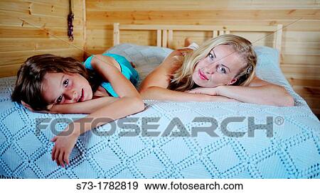 Mother and daughter lying on bed View Large Photo Image Stock Photo - Mother and daughter lying on bed. Fotosearch