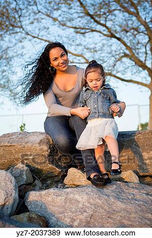 Stock Photo - Mother and Daughter on riverbank rocks, Tarrytown, New York, USA.. Fotosearch