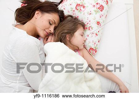 Stock Photograph - Mother and daughter sleeping in bed.. Fotosearch