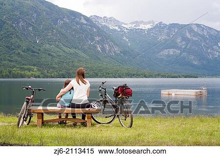 Mother and daughter together sitting on a wooden bench by the lake of Bohinj, Slovenia Gorenjska. View Large Photo Image Stock Photography - Mother and daughter together sitting on a wooden bench by the lake of Bohinj, Slovenia Gorenjska.. Fotosearch