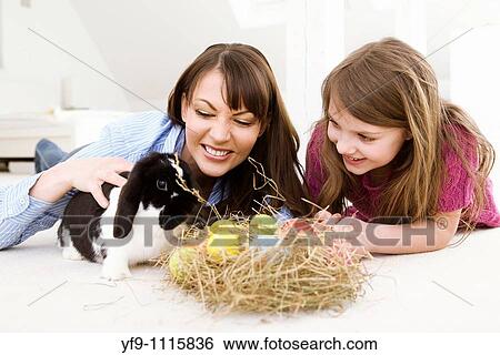 Stock Photograph - Mother and daughter with Easter eggs and rabbit.. Fotosearch