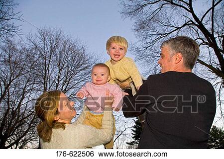 Mother and Father (husband and wife) holding their two young children up in the air. View Large Photo Image Stock Photograph - Mother and Father (husband and wife) holding their two young children up in the air.. Fotosearch