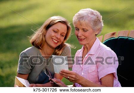 Stock Photograph - Mother and her adult daughter looking at photos. Fotosearch