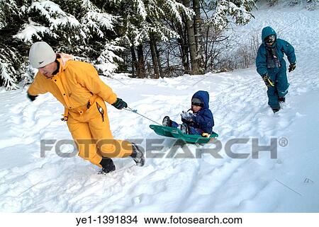 Mother and her two children playing with a sled in the snow at a ski resort in the French Alps, France View Large Photo Image Picture - Mother and her two children playing with a sled in the snow at a ski resort in the French Alps, France. Fotosearch