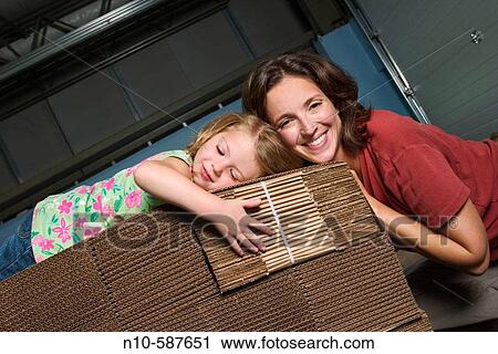 Mother and her young daughter posing together on a pile of cardboard boxes in a factory. View Large Photo Image Stock Image - Mother and her young daughter posing together on a pile of cardboard boxes in a factory.. Fotosearch