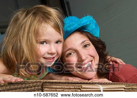 Mother and her young daughter posing together on a pile of cardboard boxes in a factory. View Large Photo Image Stock Image - Mother and her young daughter posing together on a pile of cardboard boxes in a factory.. Fotosearch