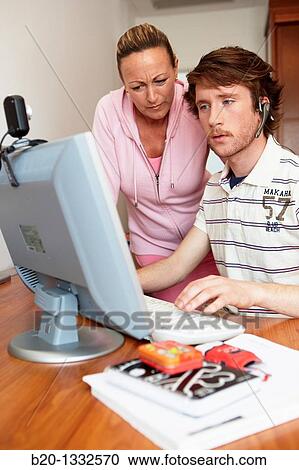 Stock Image - Mother and son looking at PC in room. Fotosearch