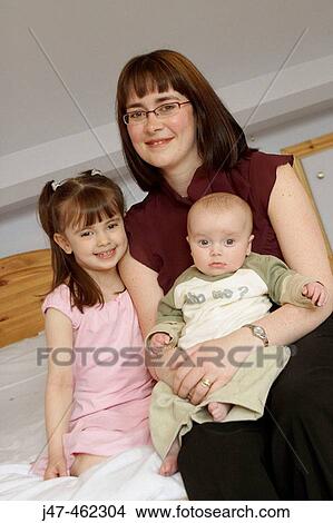 Mother and two children, ages 4 and 1, smiling into camera. View Large Photo Image Picture - Mother and two children, ages 4 and 1, smiling into camera.. Fotosearch