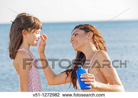 Stock Image - Mother applying sun protection cream to her daughter. Fotosearch