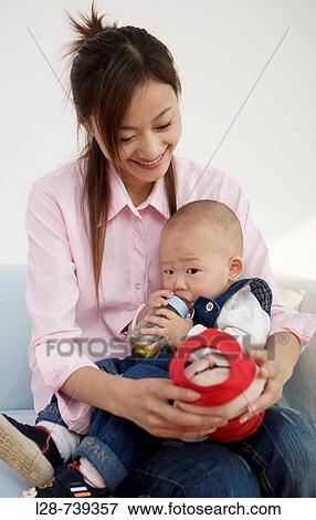 Mother Cradling Infant Daughter, Bottle Feeding View Large Photo Image Stock Photo - Mother Cradling Infant Daughter, Bottle Feeding. Fotosearch