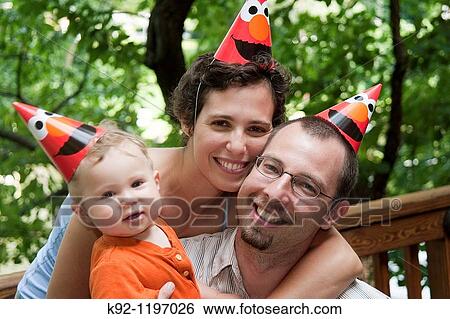 Stock Photograph - Mother, father and child with birthday hats.. Fotosearch