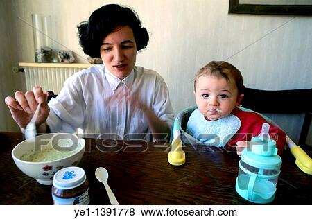 Mother feeding her baby boy at home on the dining table View Large Photo Image Stock Photo - Mother feeding her baby boy at home on the dining table. Fotosearch
