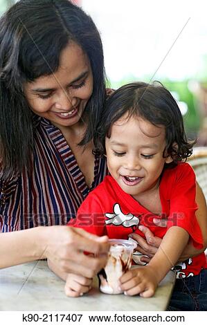 Mother feeding her son with ice cream, Jakarta, Indonesia, Southeast Asia. View Large Photo Image Stock Photo - Mother feeding her son with ice cream, Jakarta, Indonesia, Southeast Asia.. Fotosearch
