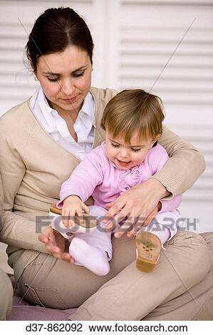 Mother helping her daughter putting her shoe on View Large Photo Image Stock Image - Mother helping her daughter putting her shoe on. Fotosearch