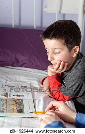 Picture - Mother helps child to read a bedtime story. Fotosearch